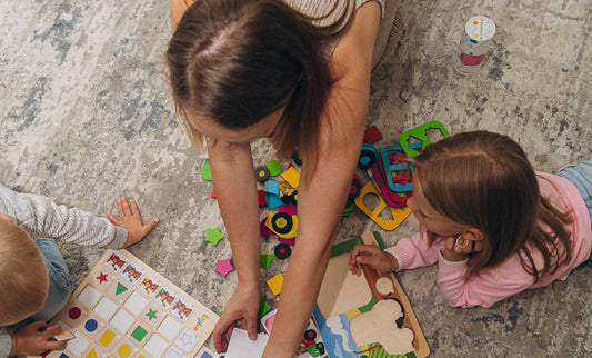 Woman and two children playing with colorful toys on a rug-covered floor.