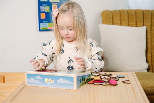 Child intensely focused while playing with a wooden puzzle toy on a table.
