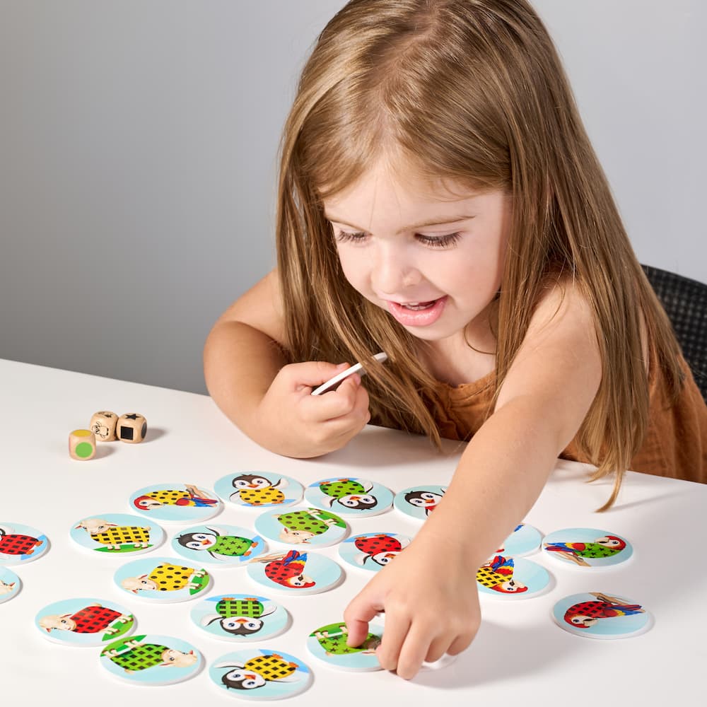 Child playing with colorful animal-picture game pieces on a table.