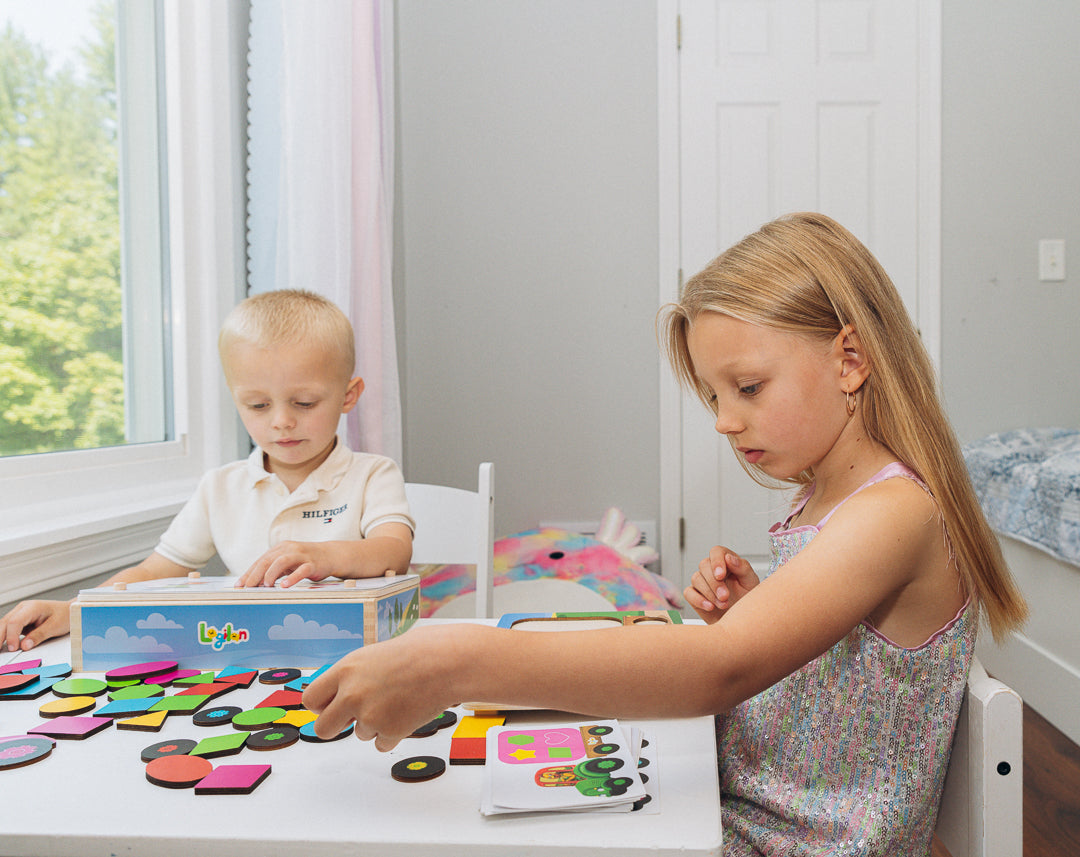 Two children playing with a colorful wooden toy set on a table.